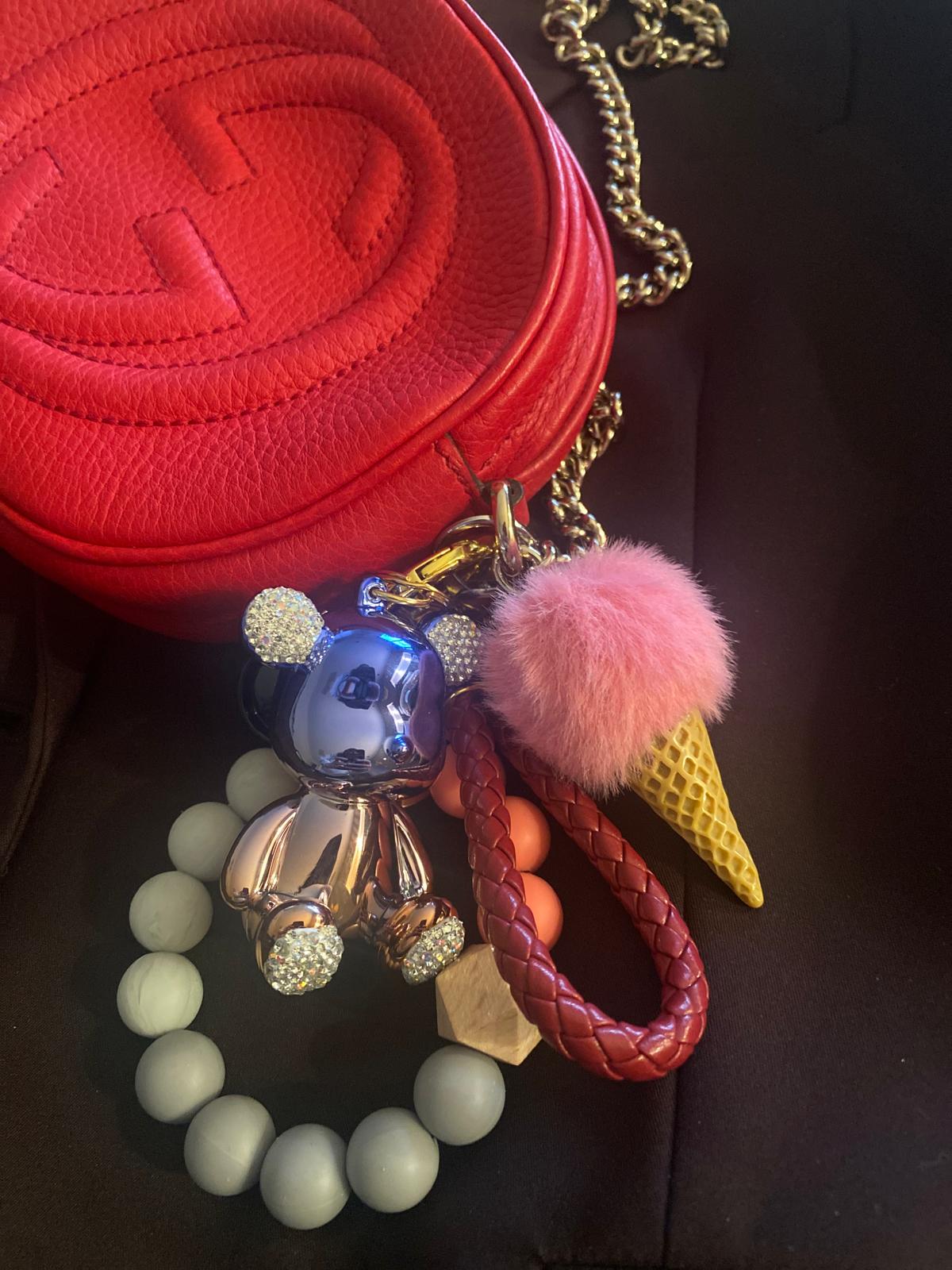 Cute and colorful ice cream-themed keychain featuring a pink pom-pom, a gold metallic teddy bear charm with diamond ears, and a beaded leather like strap.