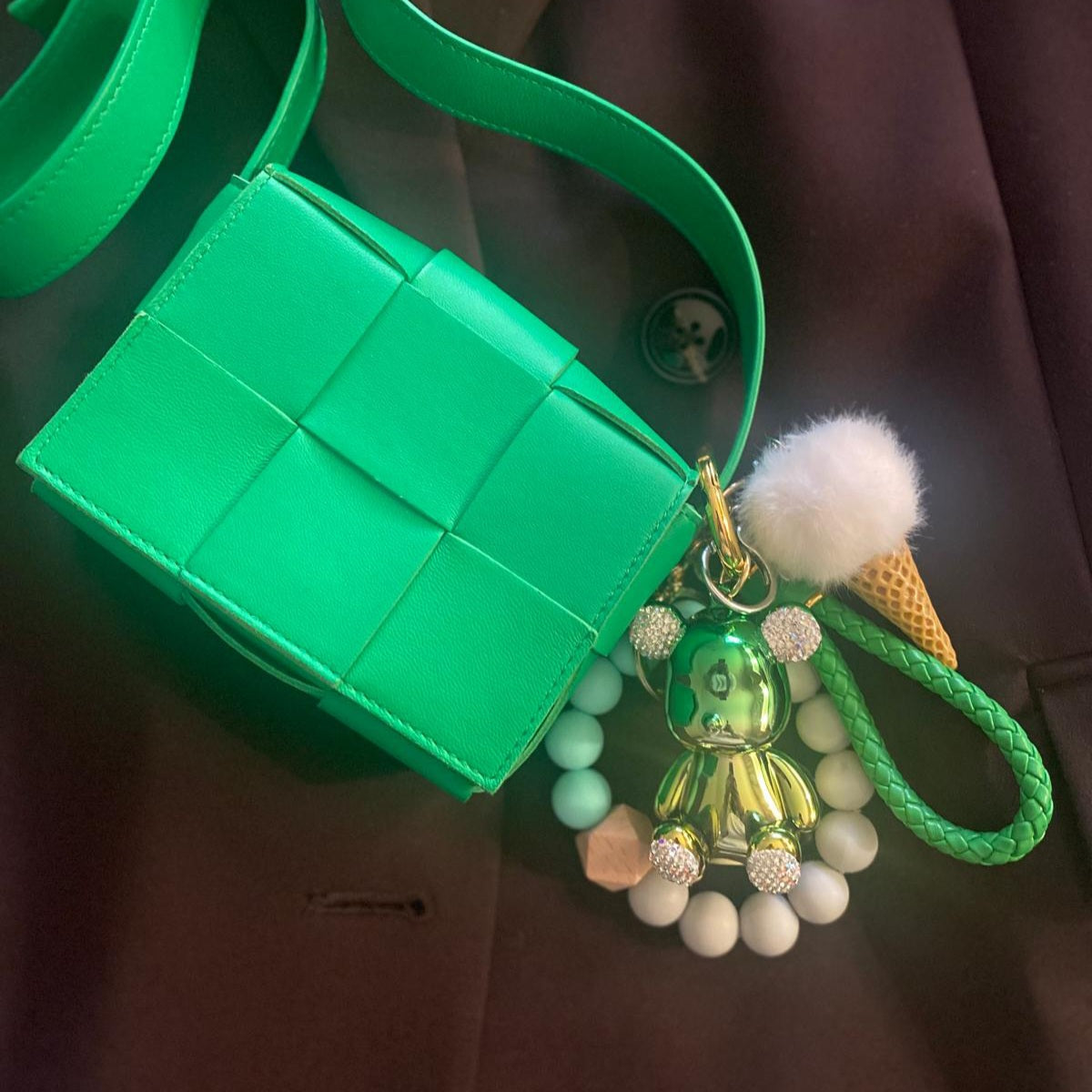 Cute and colorful ice cream-themed keychain featuring a white pom-pom, a gold metallic teddy bear charm with diamond ears, and a beaded leather like strap.