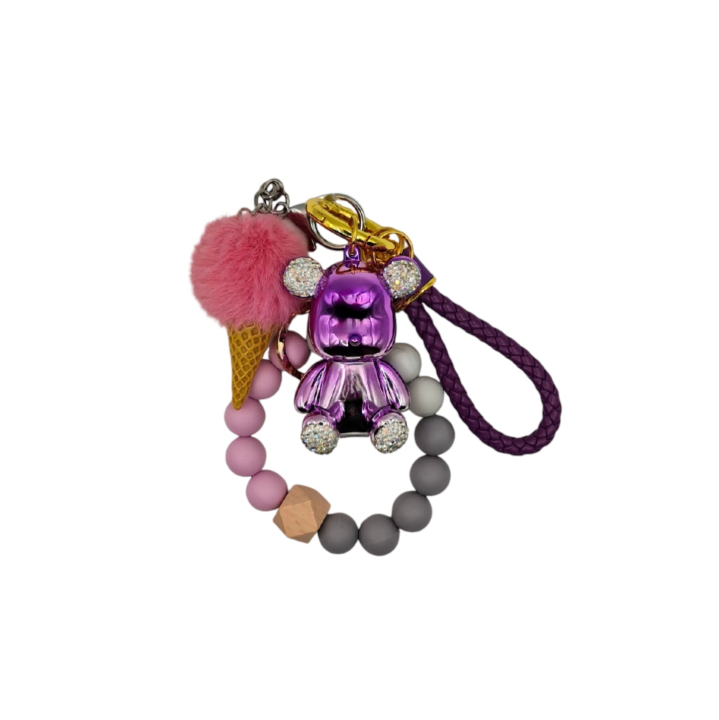 Cute and colorful ice cream-themed keychain featuring a pink pom-pom, a gold metallic teddy bear charm with diamond ears, and a beaded purple leather like strap.