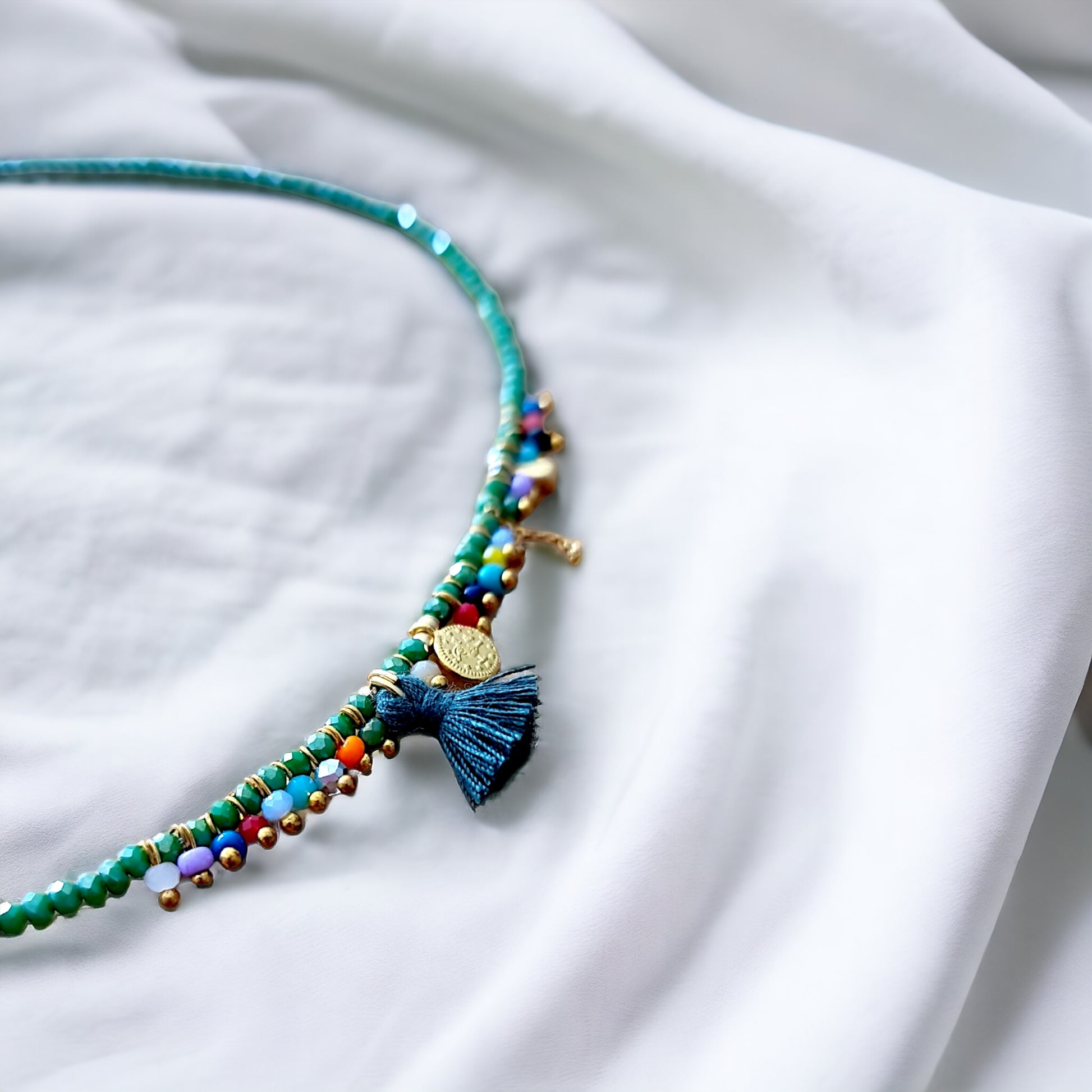 Close-up view of a green crystal costume necklace with a vibrant multicolore bead tassel, handcrafted with Arcobaleno beads.